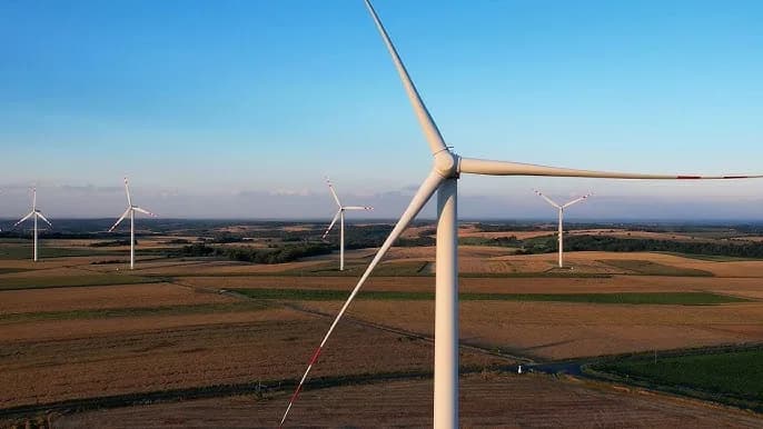 Farmy wiatrowe na rozległym krajobrazie rolniczym podczas zachodu słońca